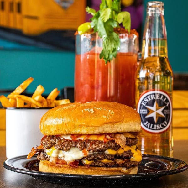 Chelito's triple cheeseburger with bacon, fries, a Michelada, and an Estrella Jalisco beer.